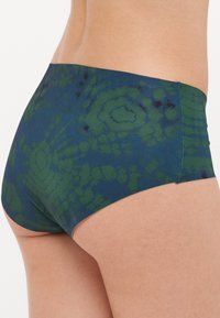 High-waisted swim shorts in dark blue and green tie-dye pattern. Smooth texture, soft fabric, with stitched detailing along the edges.