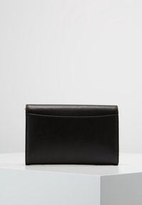 Czarna skórzana torebka kopertowa w prostokątnym kształcie. Posiada przednią kieszeń oraz gładką fakturę. Zamek błyskawiczny na górze.