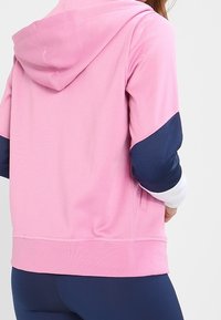 Felpa con cappuccio, corpo rosa e maniche blu navy. Presenta una tasca a marsupio e polsini a costine, realizzata in un tessuto morbido.