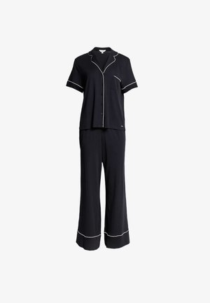 Ensemble de pyjama bleu marine comprenant un haut à manches courtes avec des bordures blanches et une poche, associé à un pantalon large avec des accents assortis.