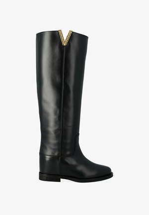 Stivale alto in pelle nera con tacco basso, finitura liscia e dettaglio decorativo dorato a forma di V sul bordo superiore.