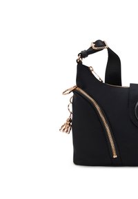 Borsa nera in nylon con hardware color oro, caratterizzata da una zip prominente su un lato e un ciondolo decorativo attaccato al cursore della zip.