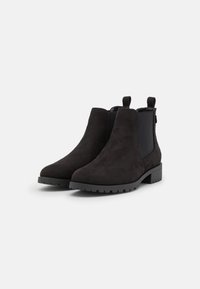 Stivaletti in suede neri con pannelli laterali in elastico e piccole linguette, dotati di una suola in gomma resistente con tacco basso a blocco.