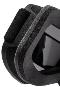 Črna penaška maska za oči z teksturirano površino in nastavljivim trakom na ježka, z izbočeno oznako "IZDELANO V ITALIJI" na materialu.