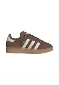 Brown suede sneaker with three white stripes, a gum sole, and a brown lacing system. Features a logo at the back and small perforations.
