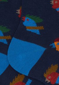 Calzini blu navy fino al ginocchio con motivi di uccelli colorati in blu, rosso e verde, con un polsino blu solido e un tessuto lavorato a maglia morbido e strutturato.