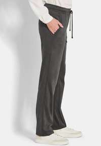 Donkergrijze sweatpants met een trekkoord in de taille, zijzakken en een gladde textuur, gecombineerd met witte sneakers.