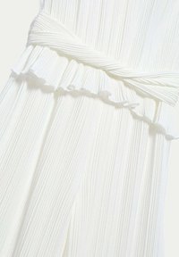 Abito in tessuto bianco plissettato con vita arricciata. Presenta un design a trama con linee verticali e aree lisce.