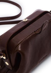 Borsa a tracolla in pelle marrone con una texture liscia, dotata di una chiusura a scatto in tonalità oro e di una sottile tracolla regolabile.