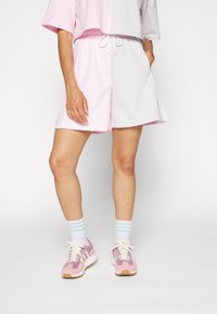 Rosa och grå träningsshorts med elastisk midja, sidofickor och en rosa cropped top. Kombinerat med rosa sneakers och randiga strumpor.