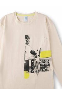 Beige long-sleeve shirt in soft cotton featuring a black and white graphic print with yellow accents, a crew neck, and a straight hem.