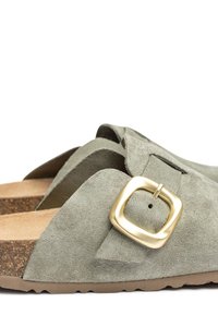Grüne Wildleder-Sandalen mit einem breiten Riemen und einer goldenen quadratischen Schnalle, ausgestattet mit einem Korkfußbett und einer strukturierten Gummisohle.