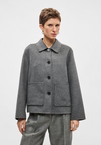 �Γκρι σακάκι από μείγμα μαλλιού με γιακά, κούμπωμα με κουμπιά μπροστά και δύο τσέπες στο πάνω μέρος. Διαθέτει άνετη εφαρμογή και ελαφρώς φαρδιά μανίκια.