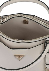 Crème leren handtas met een gestructureerd ontwerp, voorzien van een rits in goudkleur, zwarte accenten en een metalen logo-opdruk aan de voorkant.