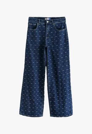 Denimbyxor med vida ben i mörkblått med ett upprepat mönster av små vita rosetter. Har fem fickor och knäppning.