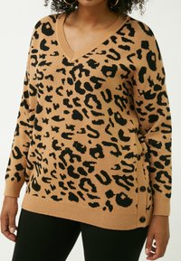 Maglione beige con stampa leopardata nera, dotato di scollatura a V e polsini a coste. I bottoni laterali aggiungono un tocco di dettaglio al design dal taglio rilassato.