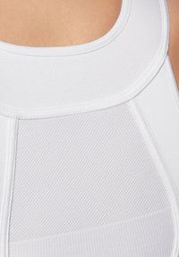 Weißes Sporttop mit einer strukturierten Blende und glattem Stoff. Der Rundhalsausschnitt betont das taillierte Design.