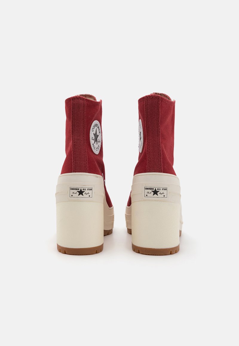 Rote Canvas-Ankle-Boots mit einer weißen Gummisohle und -ferse, die ein rundes Logopatch und kontrastierende cremefarbene Akzente an der Seite aufweisen.