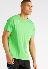 Groene sportt-shirt van glad, vochtregulerend materiaal. Heeft een ronde hals en een logo op de borst. Korte mouwen, losse pasvorm.