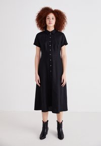 Rochie neagră cu buton, cu mâneci scurte, guler și lungime midi, realizată dintr-un material ușor, cu o textură netedă.