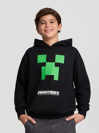 Felpa nera con cappuccio in cotone, con una grande faccia pixelata verde di creeper sul davanti e il logo bianco "Minecraft" sulla tasca.