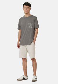 Grijs katoenen t-shirt met een zak, voorzien van een botanische print, gecombineerd met witte shorts en multicolore sneakers. Casual pasvorm en ontwerp.