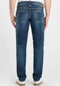Jeans de mezclilla azul oscuro con corte slim, que cuentan con dos bolsillos traseros y costuras en contraste. Destacados con una parche de cuero en la cintura.