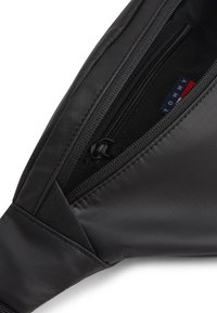 Fekete szövet táska texturált felülettel, cipzáras zsebbel és belül látható logócímkével. Tartós és könnyű kialakítás.