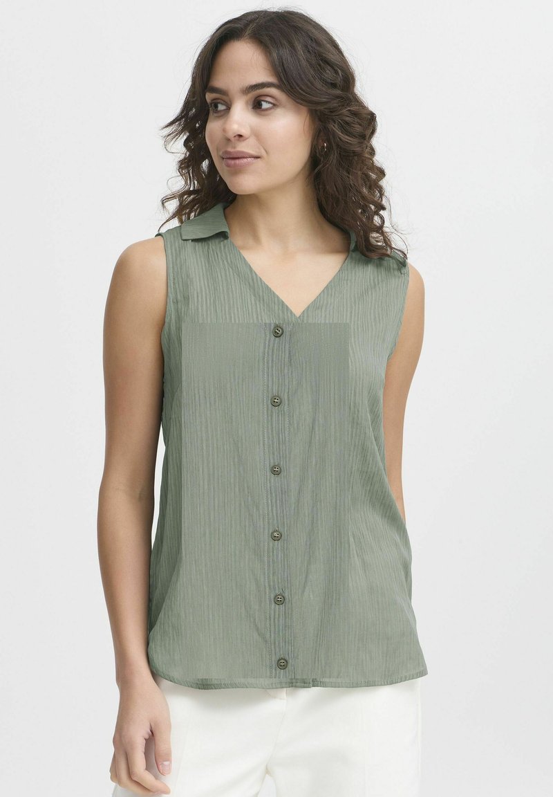 Beigalinė žalia palaidinė su V formos iškirpte, vertikaliomis juostelėmis tekstūra ir mygtukų užtrauktuku. Lengvas audinys su subtiliu blizgesiu ir apykaklės detale.