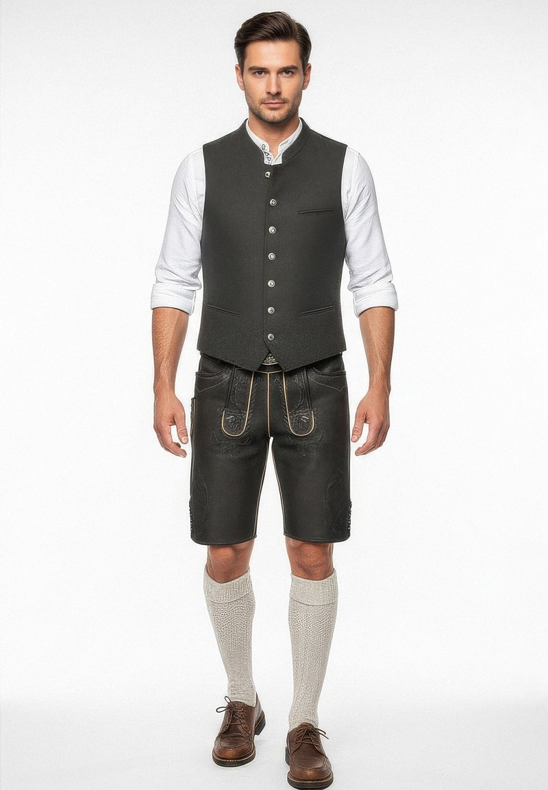 Tmavě zelená vesta, bílá košile s dlouhým rukávem, černé kožené šortky se žlutými akcenty, šedé ponožky do délky kolen a hnědé boty.