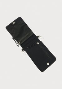 Μαύρο υφασμάτινο πορτοφόλι με υφή στην επιφάνεια, διαθέτοντας θήκη με φερμουάρ, κουμπί με πάτημα και δύο κλιπς για πρόσδεση.