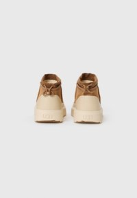 Bruine suède enkellaarsjes met beige rubberen zolen en elastische bovenranden. Voorzien van een lichte voering en decoratieve trekkoordhardware.