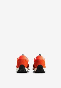 Scarpe sportive con una vivace tomaia in suede arancione, suola in gomma nera e accenti bianchi. Forma arrotondata, design senza lacci e linguette per il sollevamento.