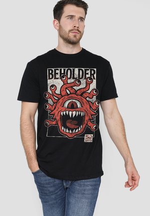Schwarzes Baumwoll-T-Shirt mit einem großen roten Monster-Graphic, das mehrere Augen, detaillierte Fangzähne und das Wort "BEHOLDER" in fettem Text darüber zeigt.