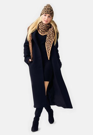 Long black coat over a ribbed black dress. Accessorized with a leopard-print scarf and hat in shades of brown and tan. Black heeled boots.