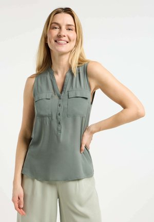 Top senza maniche a scollo a v in verde tenue, dotato di due tasche sul petto, una chiusura a bottoni e una texture liscia. Abbinato a pantaloni chiari.