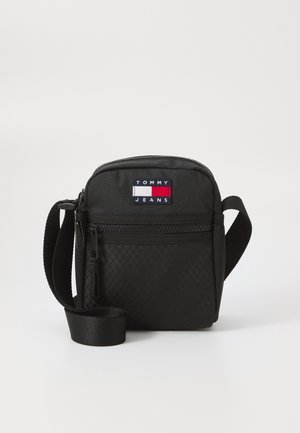 Lille sort crossbody taske med frontlynlåslomme og justerbar rem, med Tommy Jeans logo patch foran.