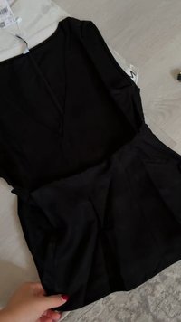 Abito nero con corpetto aderente e gonna svasata; maniche corte, tessuto morbido, scollatura a V e tasche laterali per una maggiore funzionalità.