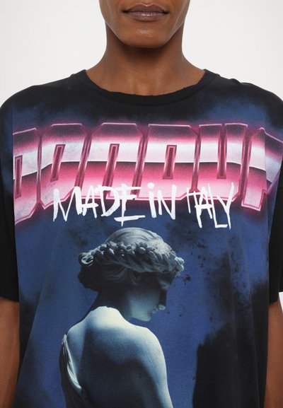Camiseta negra con un gran gráfico que muestra el texto "DADDY" en rosa y "HECHO EN ITALIA" en blanco, junto con una imagen azul de una estatua.