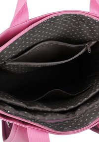 Pink tote bag with a zipped closure, featuring a grey polka dot lining and multiple interior compartments, including a zipped pocket.