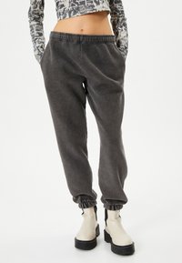 Donkergrijze jogpants met een elastische tailleband en geribde enkelmanchetten, gemaakt van een zachte stof, met twee zijzakken.