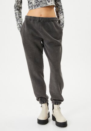 Donkergrijze jogpants met een elastische tailleband en geribde enkelmanchetten, gemaakt van een zachte stof, met twee zijzakken.