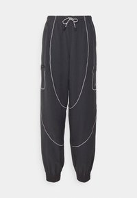 Pantalones de chándal negros con puños elásticos, que presentan patrones de costura blanca y bolsillos laterales con cremalleras. Cintura con cordón ajustable.