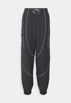 Pantalones de chándal negros con puños elásticos, que presentan patrones de costura blanca y bolsillos laterales con cremalleras. Cintura con cordón ajustable.