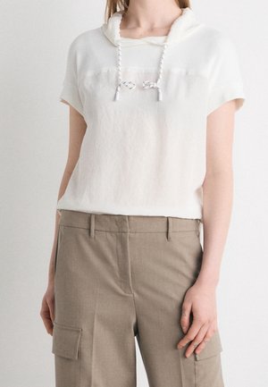 Witte hoodie met korte mouwen en trekkoorden, gecombineerd met hoog getailleerde beige cargobroek met zijzakken.