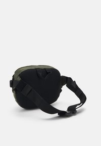 Zöld nylon táska texturált fekete hálós háttal, állítható pánttal és felső fogantyúval. Cipzárral záródik. Kompakt, kerek forma.