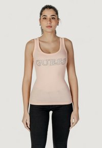 Top senza maniche rosa chiaro con la scritta "GUESS" in lettere argentate sul petto. Design aderente, materiale elasticizzato e spalline larghe.