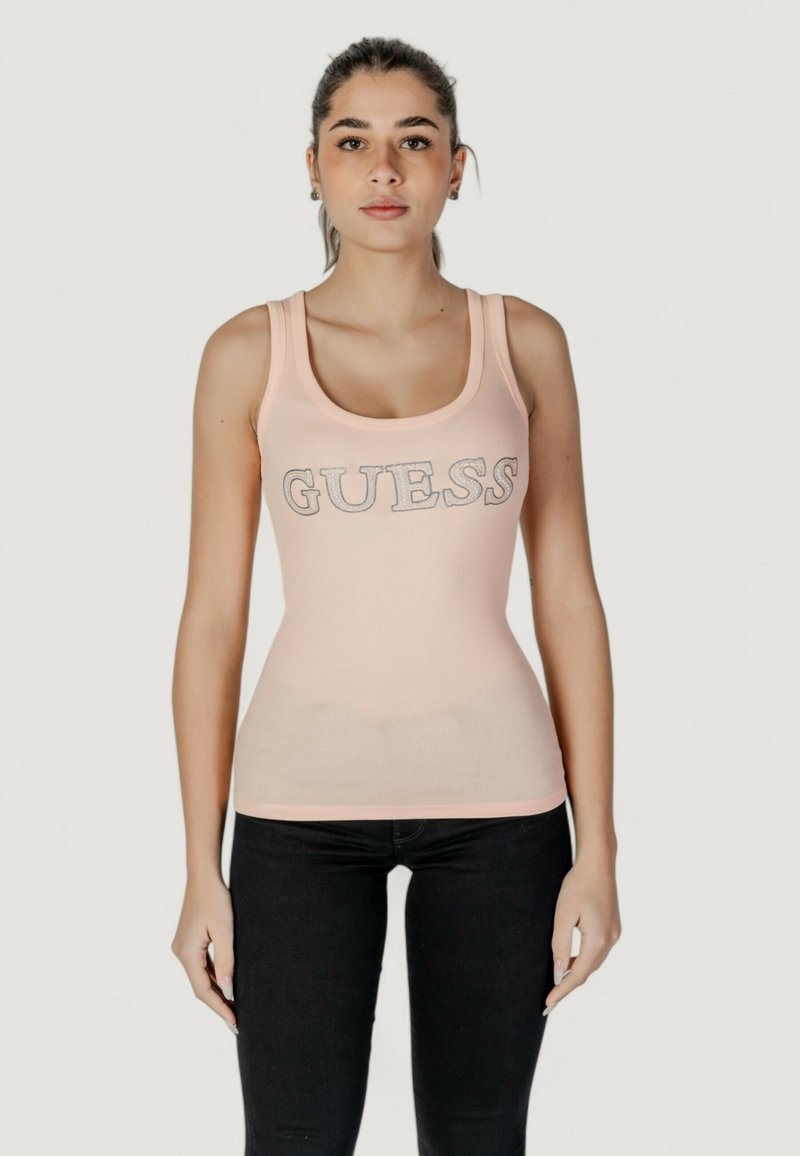Top senza maniche rosa chiaro con la scritta "GUESS" in lettere argentate sul petto. Design aderente, materiale elasticizzato e spalline larghe.