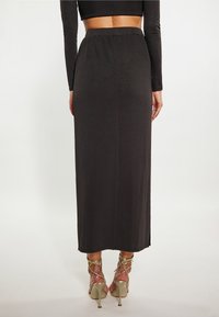 Zwarte, enkellange rok met een elastische tailleband en een gladde textuur. Draag het met gouden, strappy hoge hakken.