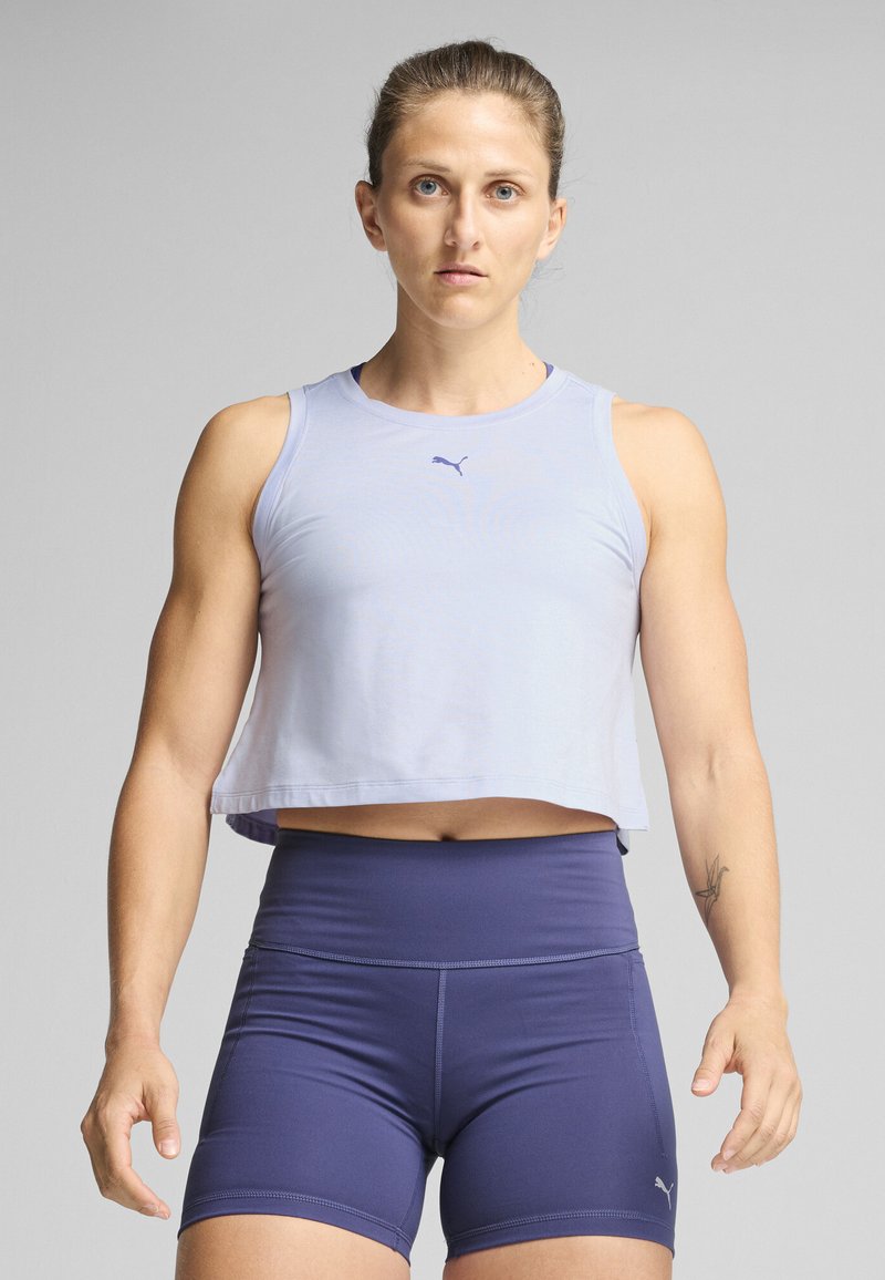 Licht paarse cropped sport tanktop met een klein logo, gecombineerd met hooggewaaid donker marineblauwe shorts; zachte stof, minimalistisch ontwerp.